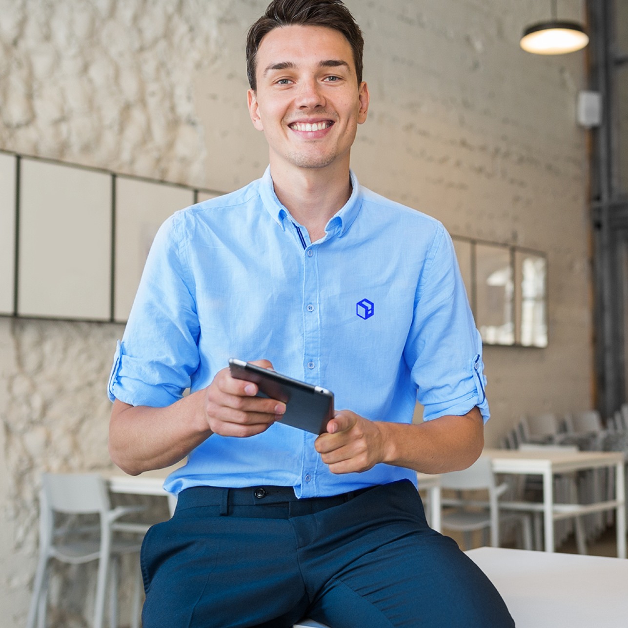 Profissional da Loginfo com camisa azul e o símbolo bordado, segurando um tablet