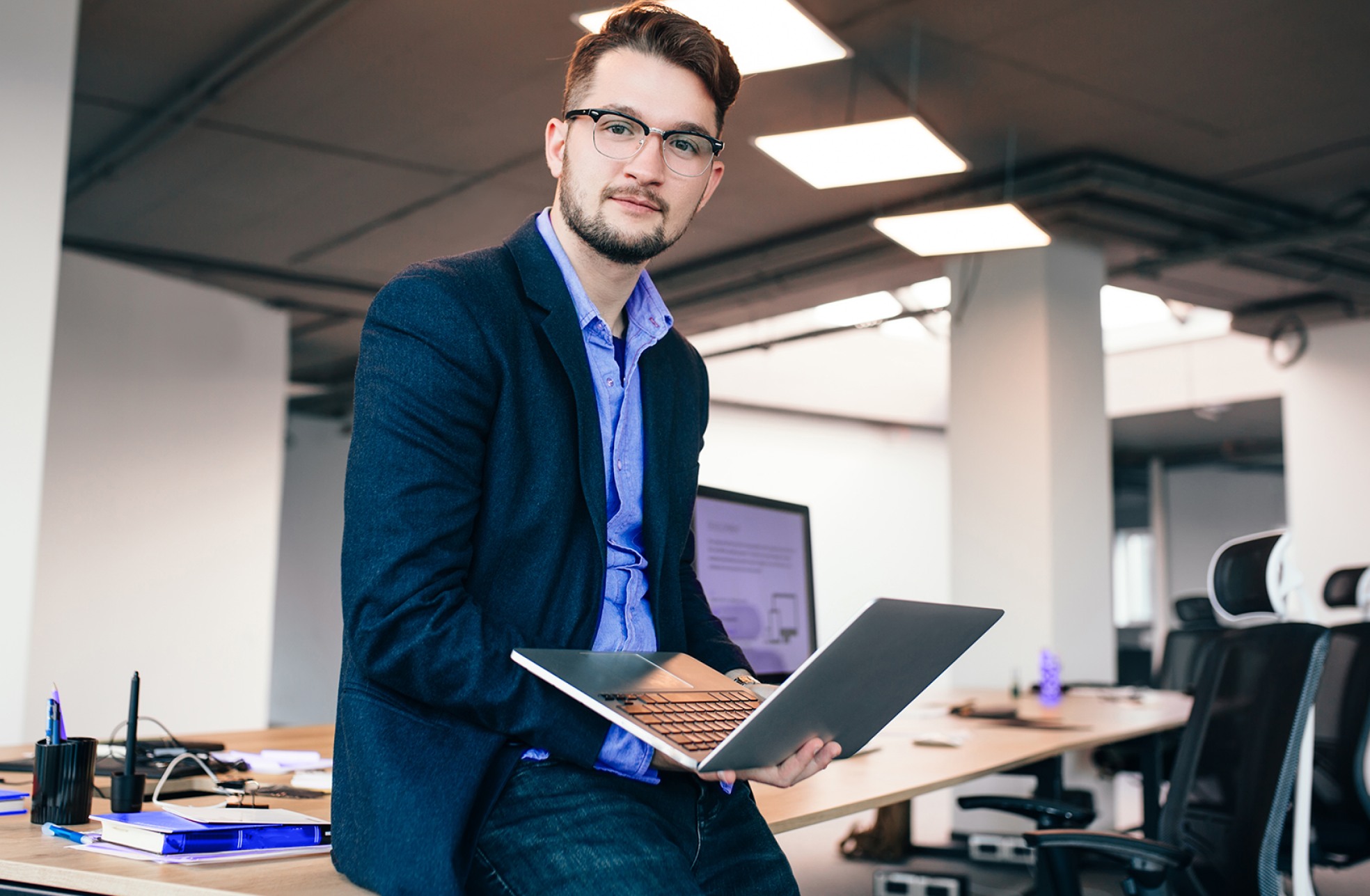 Profissional de blazer sentado na mesa do escritório com um notebook