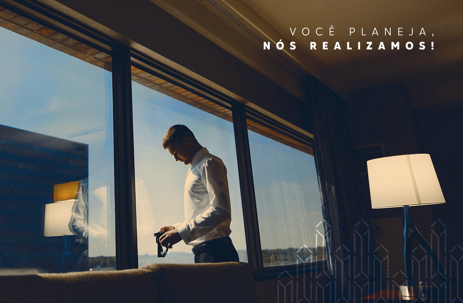 Homem se arrumando diante da janela, com o padrão dos prédios e a frase Você planeja, nós realizamos